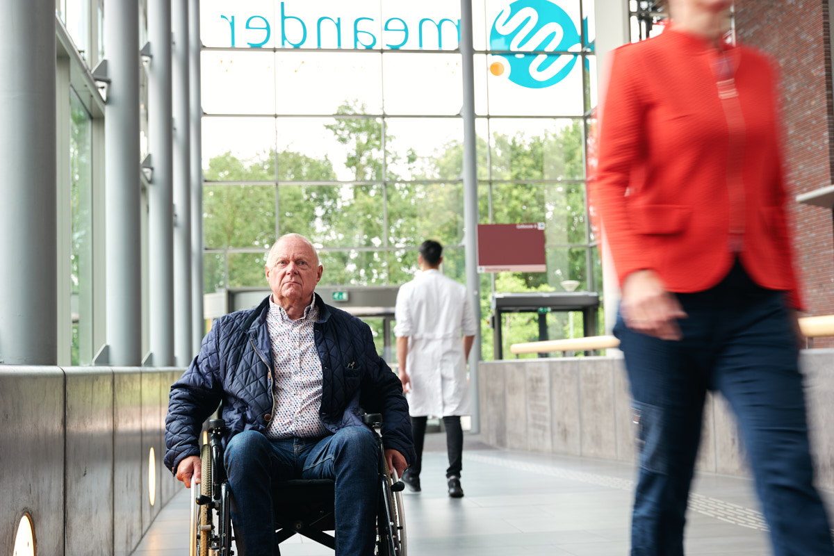 Man in rolstoel in hal van ziekenhuis